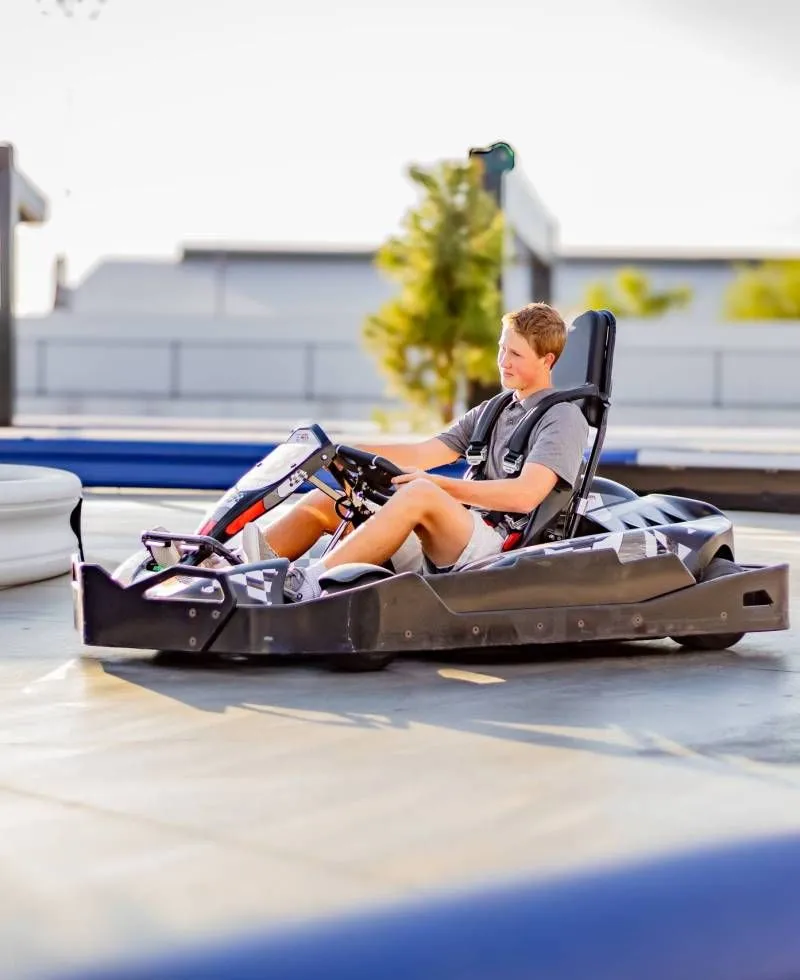 Person driving a black go-kart on a sunny outdoor track