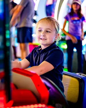 Smiling child on a kiddie ride in the arcade