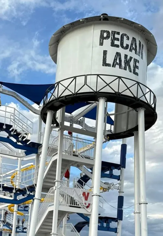 Peach Lake water tower with bold black lettering above a blue-and-white amusement ride structure