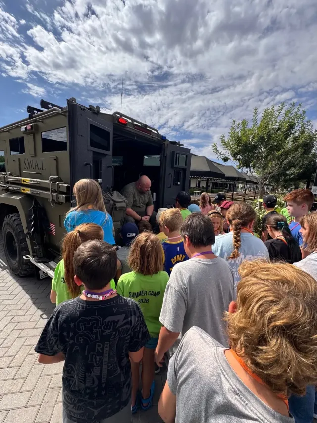 Students gathered around a S.W.A.T. vehicle during a summer camp group visit in Queen Creek, Arizona